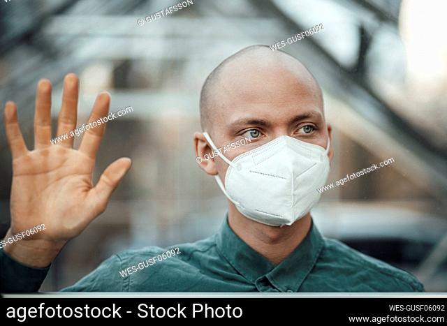 Businessman with protective face mask behind cafe window