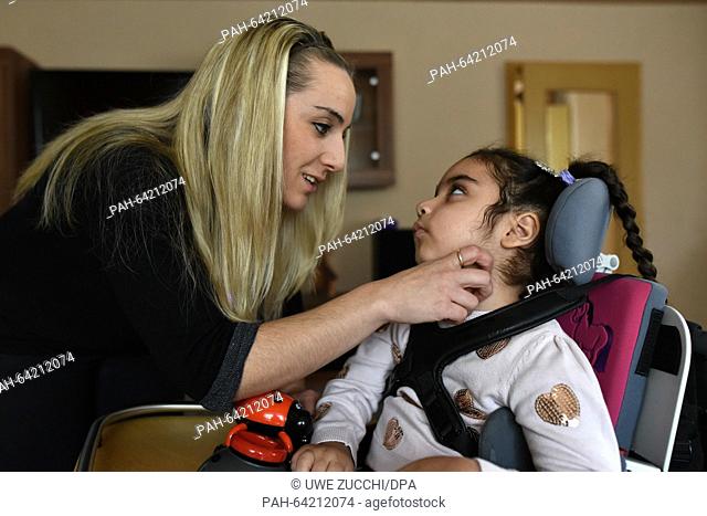 Mirella Kunzmann (l) strokes the cheak of her daughter Aliana sitting in a wheelchair in Bad Hersfeld, Germany, 2 December 2015