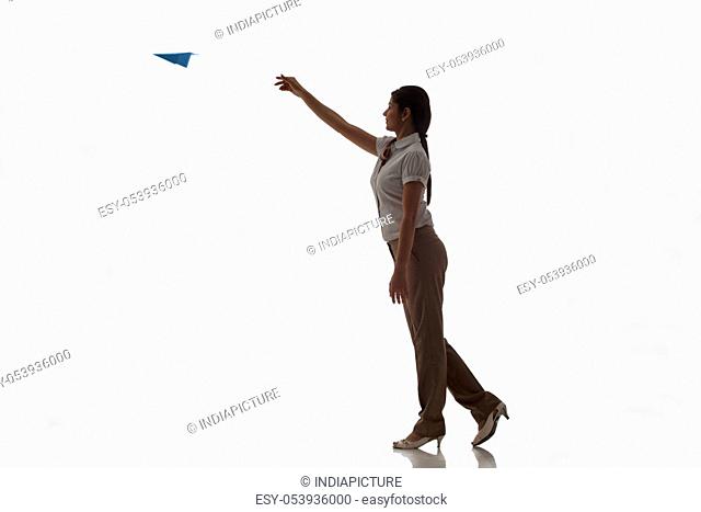 Full length of businesswoman throwing airplane in air