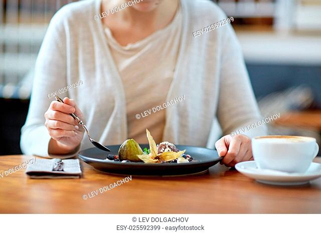 food, new nordic cuisine and people concept - woman eating chocolate ice cream dessert with blueberry kissel, honey baked fig and greek yoghurt with coffee at...