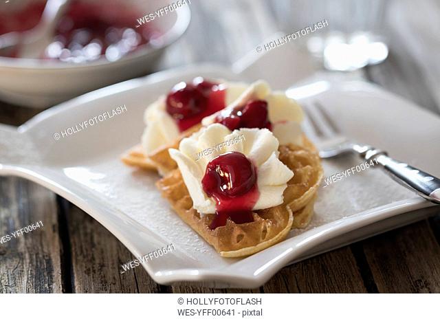 Plate of waffles with whipped cream, cherries and cherry groats