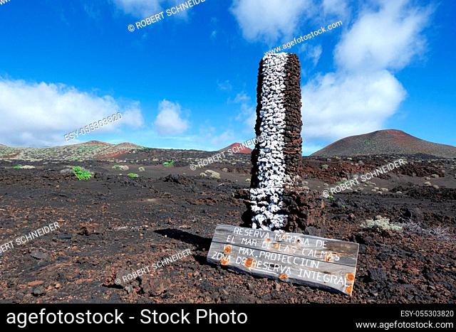 Stone pillar with wooden sign in the volcanic landscape of El Hierro, Canary Islands, near La Restinga