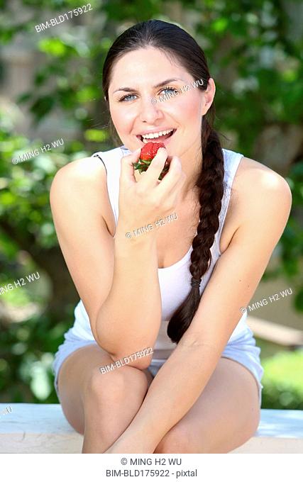 Caucasian woman eating strawberry outdoors