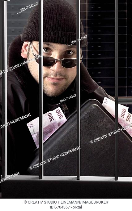 Burglar in a vault carrying a briefcase stuffed with cash