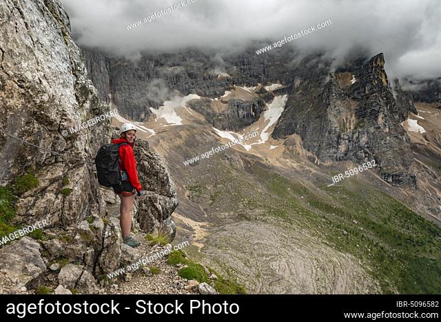 Young woman, hiker climbing a via ferrata Vandelli, Sorapiss circuit, mountains with low clouds, Dolomites, Belluno, Italy, Europe
