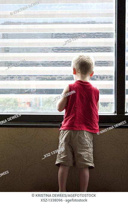 A young boy looking out a high window