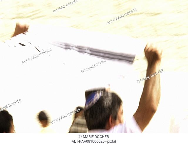Israel, Jerusalem, man holding tallith above head, blurred