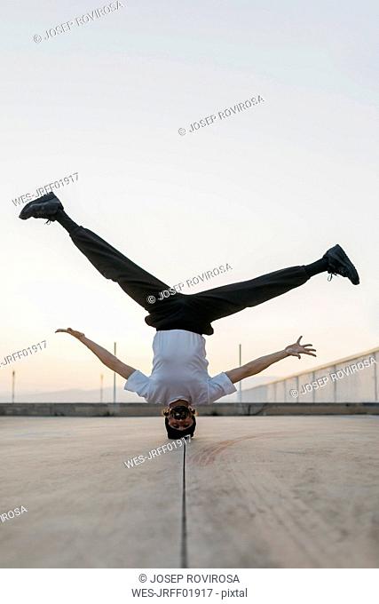 Man doing breakdance in urban concrete building, standing on head