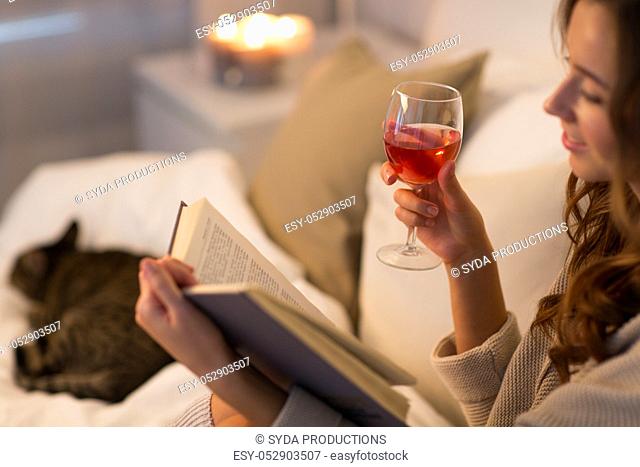 happy young woman reading book in bed at home