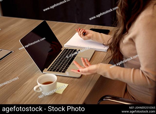 Mid section of businesswoman sitting at meeting table