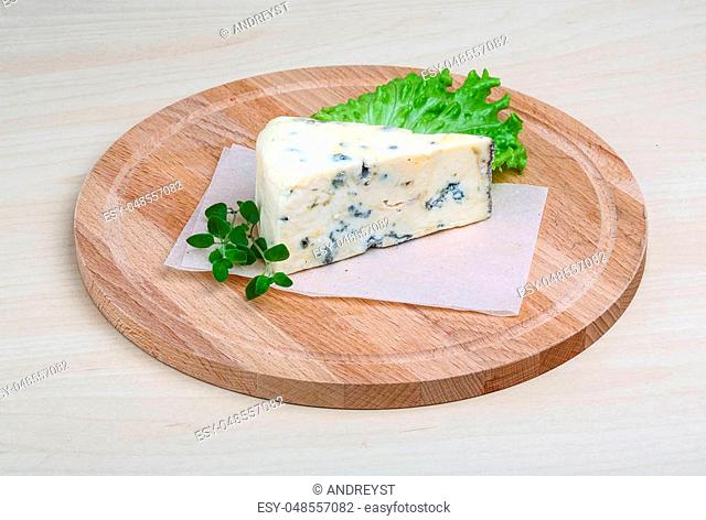 Blue cheese with oregano and salad leaves on wood background