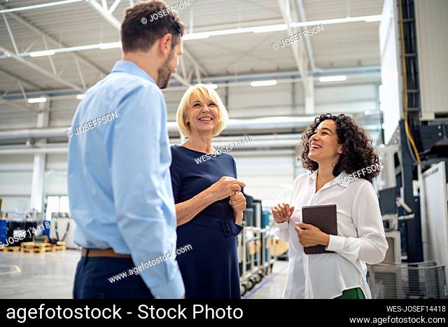 Happy businesswoman discussing with colleagues in industry