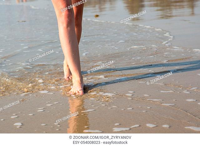 A woman walking along the beach on a Sunny day