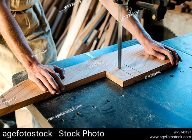 Close-up on carpenter using band saw to cut out piece of wood