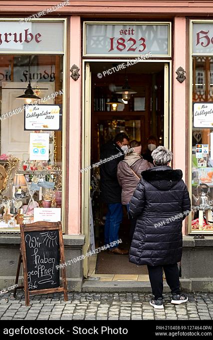 08 April 2021, Hessen, Alsfeld: Customers stand in front of and in a shop. The city in the Vogelsbergkreis has begun its model project to test ffnungsschritte...