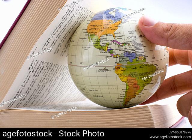 Child holding a globe in a book on a white background