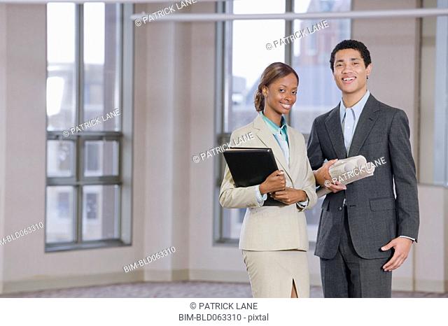 Multi-ethnic business people holding blueprints and binder