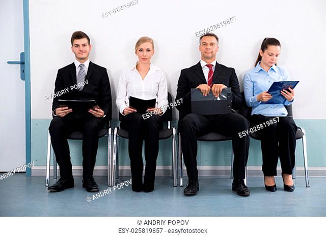 Group Of Businesspeople With Files Sitting On Chair For Giving Interview