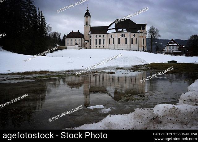 29 January 2021, Bavaria, Steingaden: The Wieskirche is reflected in the melt water on a meadow. Photo: Karl-Josef Hildenbrand/dpa
