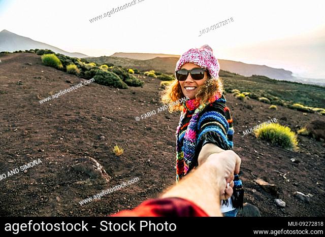 Beautiful cheerful adult young woman smile and holding man hand during outdoor leisure activity trekking at the mountain - travel couple concept for active...