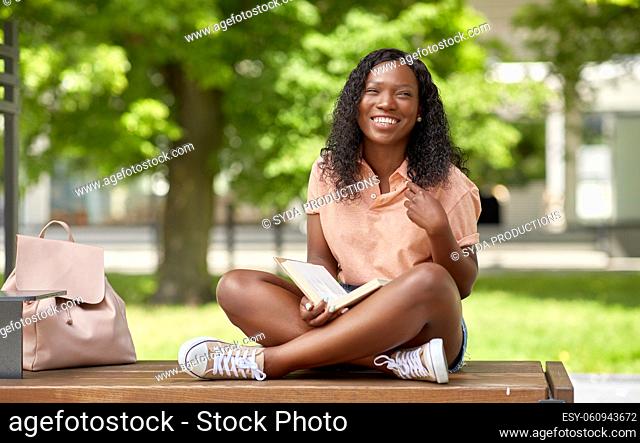 happy african student girl reading book in city