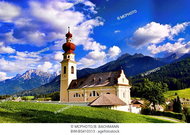 St Stephan Church with steeple with Dolomites mountains behind in Niederdorf Italy near Dobbiaco, Italy, South Tyrol, Dolomites, Dobbiaco
