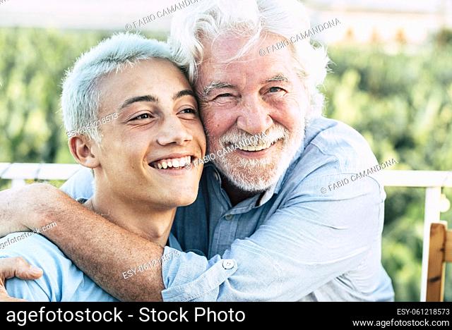 Father and son or grandfather and grandson together hug and enjoy with smile - cheerful different age caucasian people in outdoor - concept of ages and mixed...