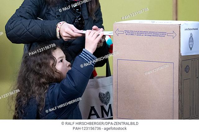 A child helps during the polls in the presidential primaries at a polling station in Buenos Aires. Eight candidate pairs compete in the area code