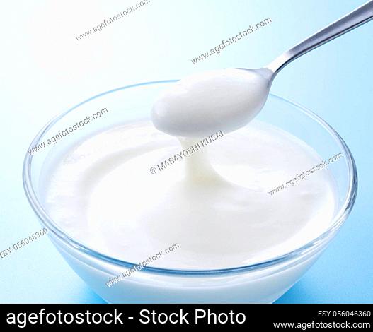 Yogurt in a glass bowl and a spoonful of yogurt