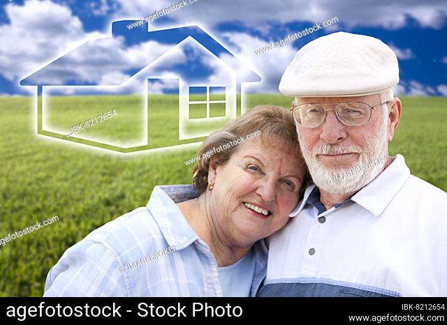 Loving senior couple standing in grass field with ghosted house on the horizon