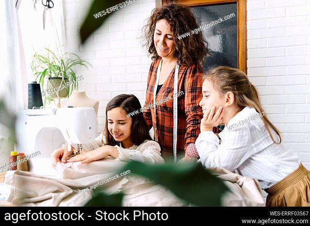 Mother and two daughters sewing at home