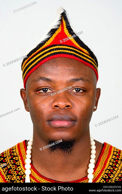 Studio shot of young handsome African man wearing traditional clothing against white background