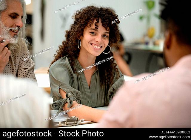 Adult female entrepreneur looking at the camera while sitting at table