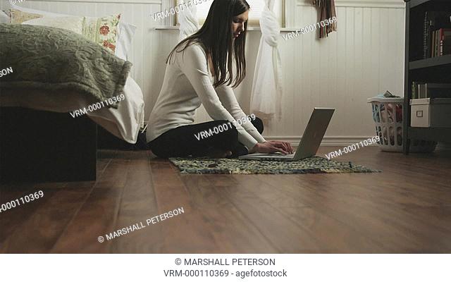 woman using a laptop in her bedroom