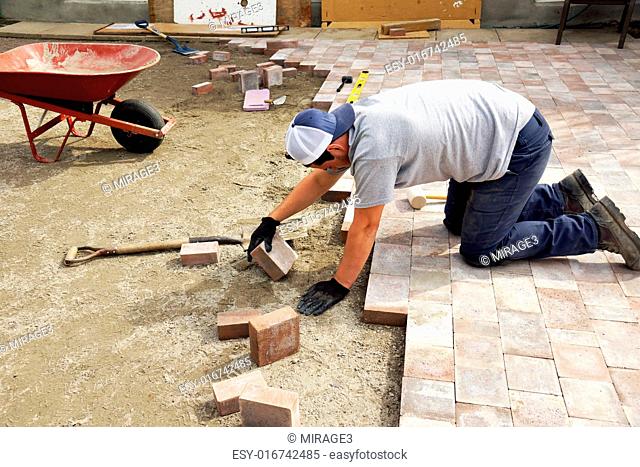 Young man laying down paver as part of landscaping