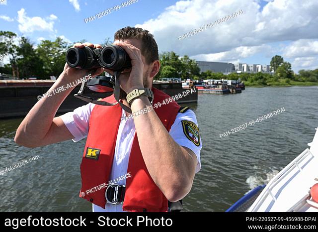 27 May 2022, Saxony-Anhalt, Magdeburg: On the Elbe near Magdeburg, Inspector Robin Boretzki observes shipping traffic. The water police are currently carrying...