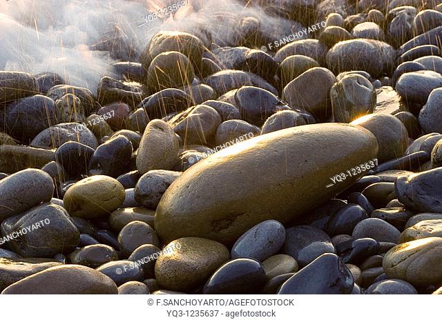 Los primeros rayos del sol centelleando entre las piedras en la costa de Mioño, Castro Urdiales, Cantabria