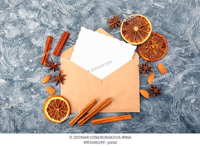 Envelope with greeting card and spices - cinnamon, anise stars, dried oranges and almonds. Flat lay. Top view
