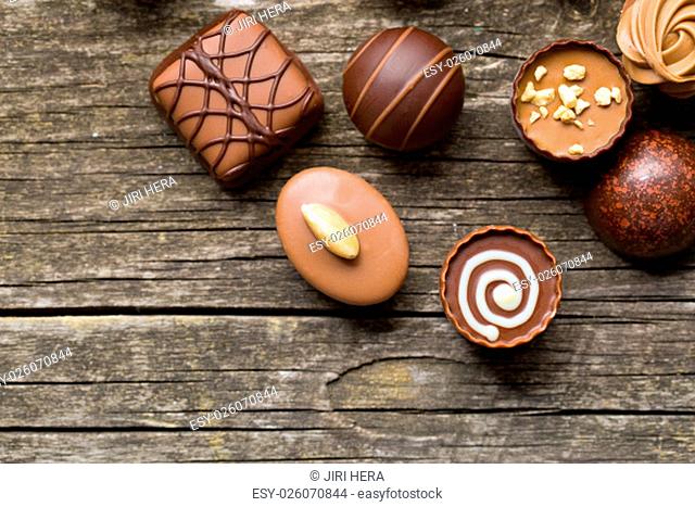 various chocolate pralines on old wooden table