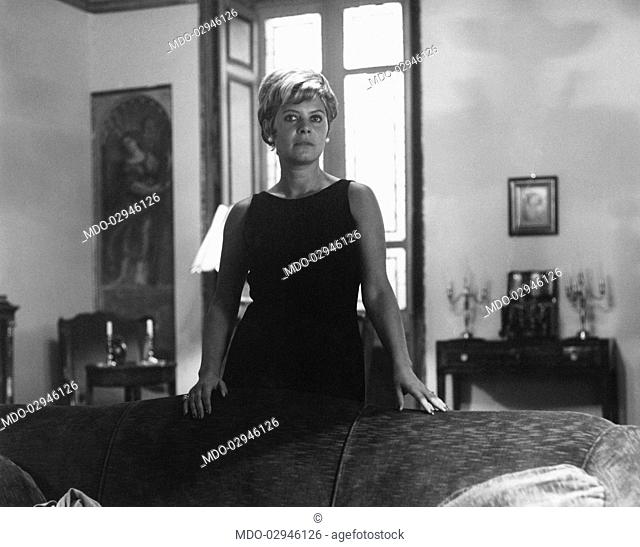 Italian actress and journalist Lianella Carell posing beside a couch. Rome, 1963