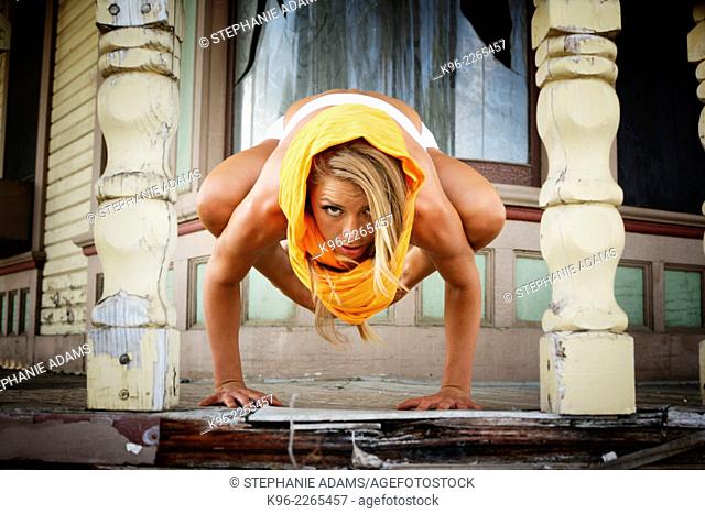 Female on old porch of a house holding a difficult yoga pose