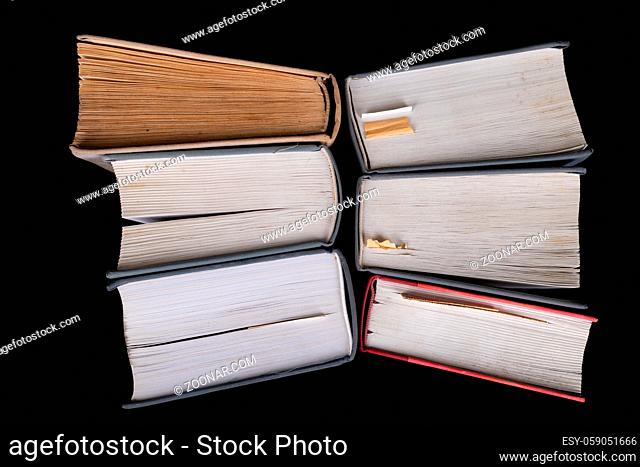 An open large book against the backdrop of a row of paper publications. Heap of old books and guides. Dark background