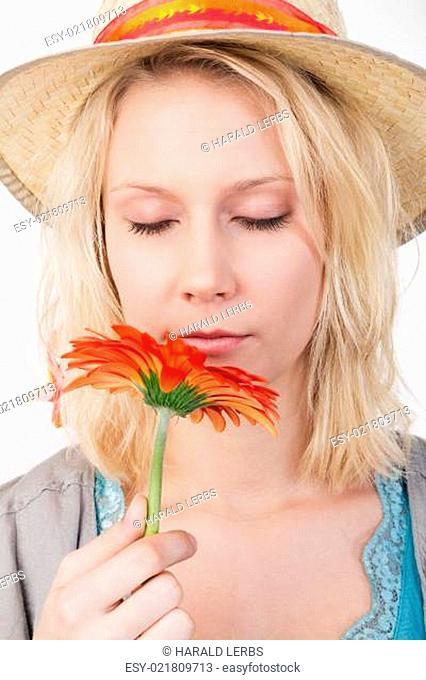 Hübsche blonde Frau riecht an einer Blume