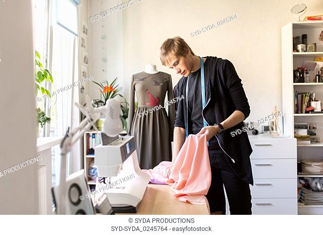fashion designer with cloth making dress at studio