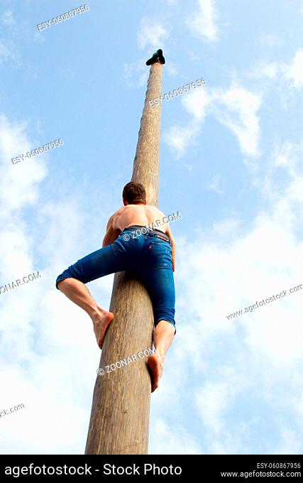 Belarus, Gomel, on March 12, 2016. Central square. Celebration of carnival. The man climbs on the pillar. Maslenitsa