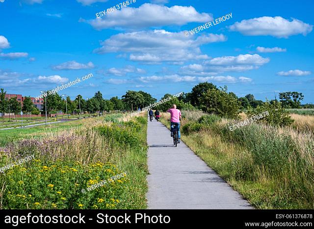 Groningen, The Netherlands - People driving the bike through the nature reserve around the city over blue sky