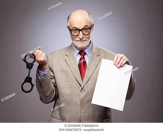 Senior man with handcuffs and paper