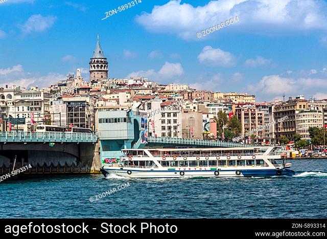 ISTANBUL - MAY 24, 2013: Tourist boat floats past the Galata tower at sunset on may 24, 2013 in Istanbul, Turkey. Golden Horn and the historic Galata area...