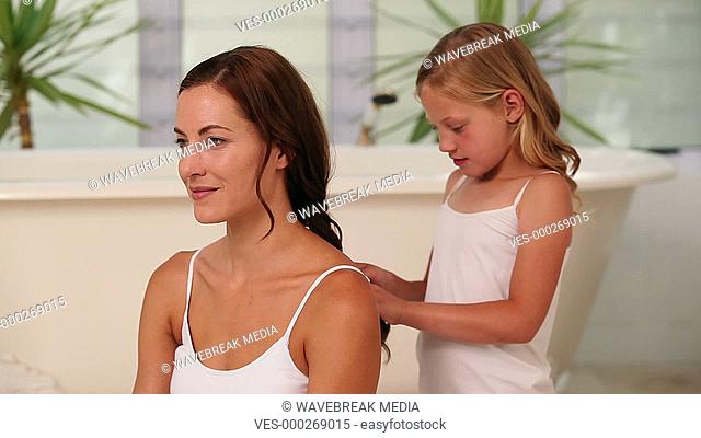 Little girl plaiting her mothers hair in the morning