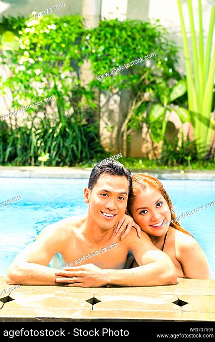 Asian couple swimming in hotel or club pool